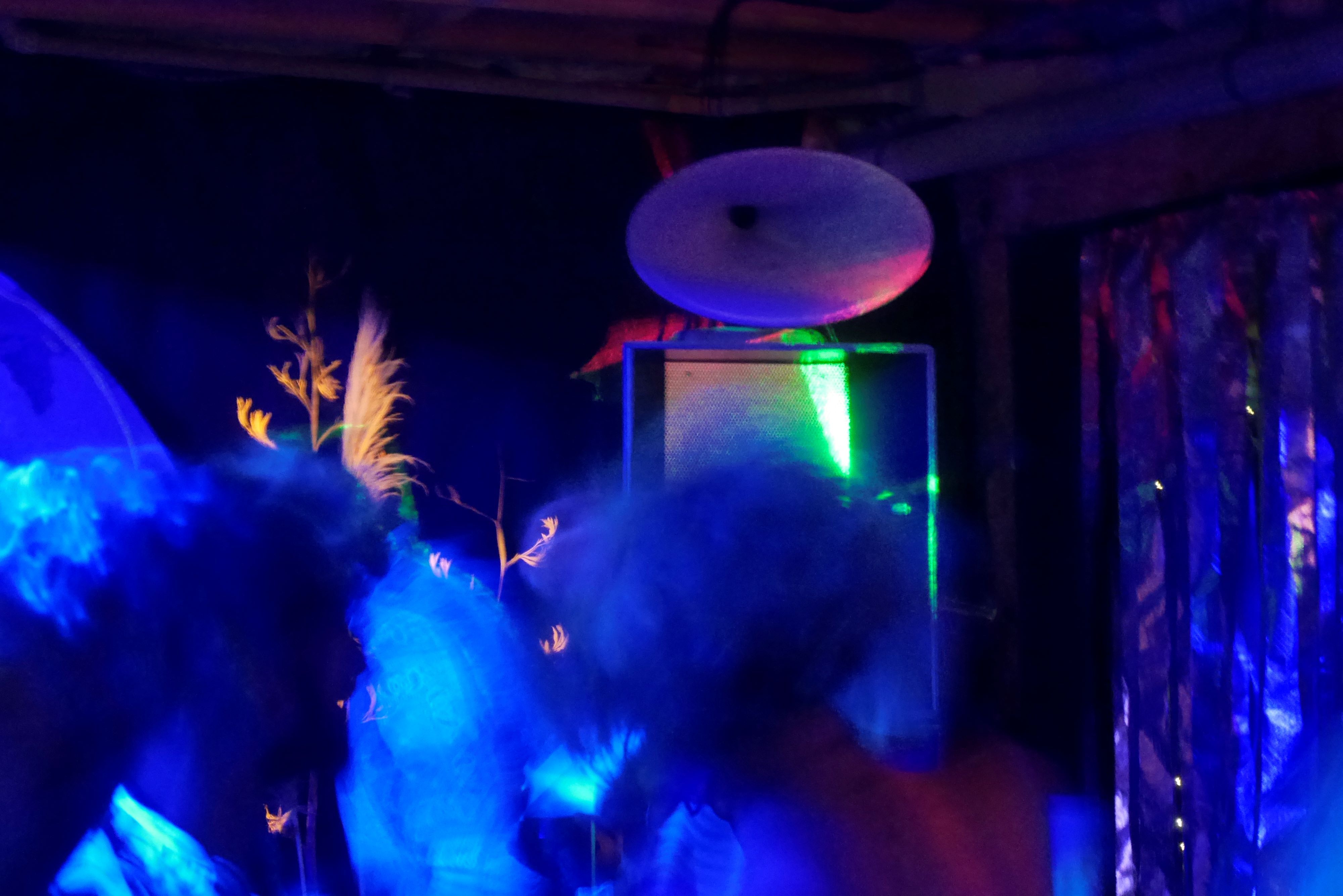 A blue-lit shot of one of the stacks, partly hidden behind blurred dancing figures